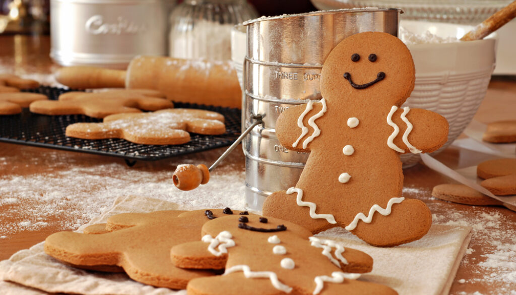 Smiling,Gingerbread,Man,Standing,Next,To,Flour,Sifter,With,Baking