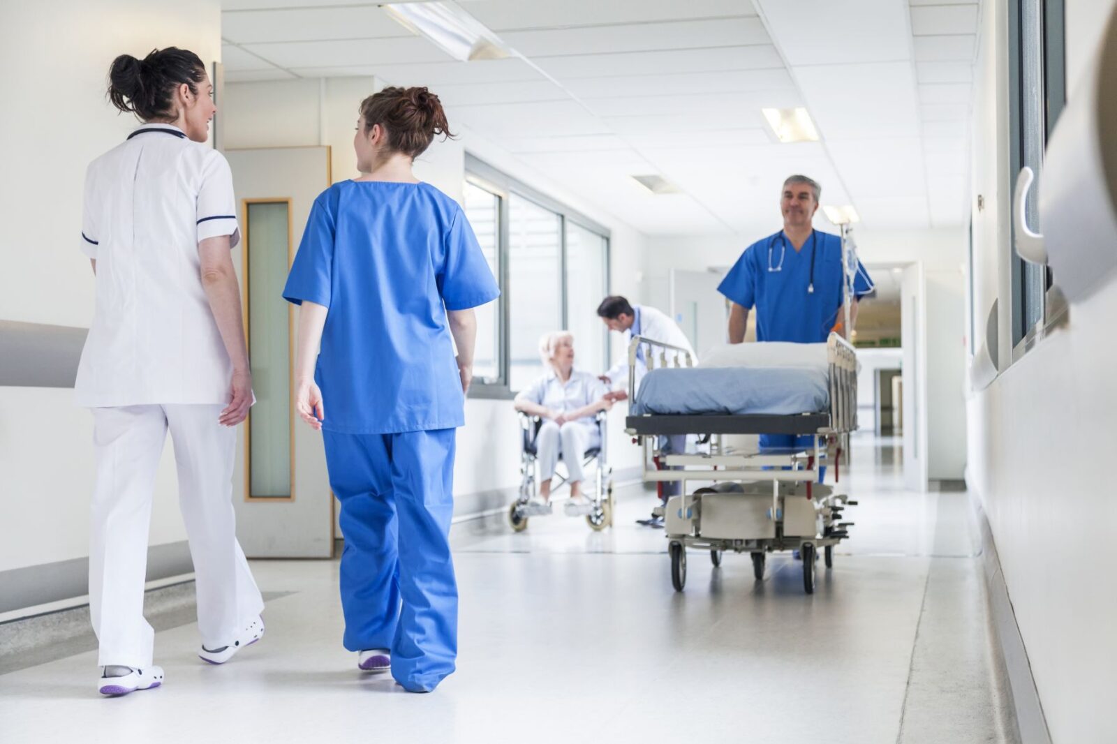 Male,Nurse,Pushing,Stretcher,Gurney,Bed,In,Hospital,Corridor,With Male,Nurse,Pushing,Stretcher,Gurney,Bed,In,Hospital,Corridor,With