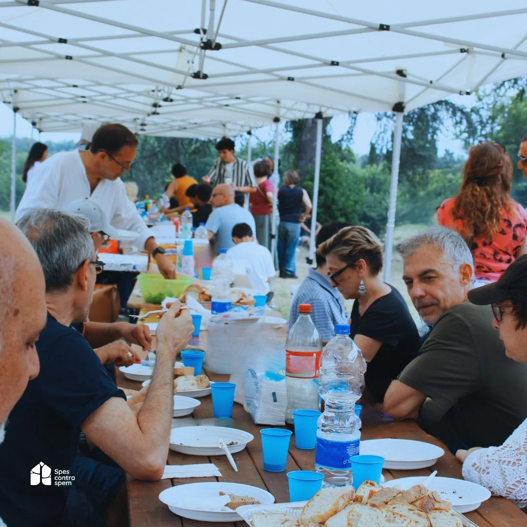 Volontari, operatori e persone accolte condividono un pranzo all’aperto durante una giornata di Spes contra spem